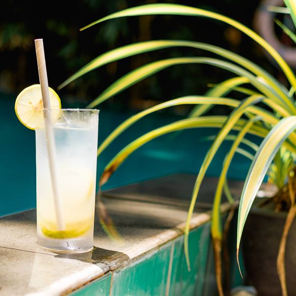 A tall glass of fresh lime juice on the edge of the pool at Amber Poolside.