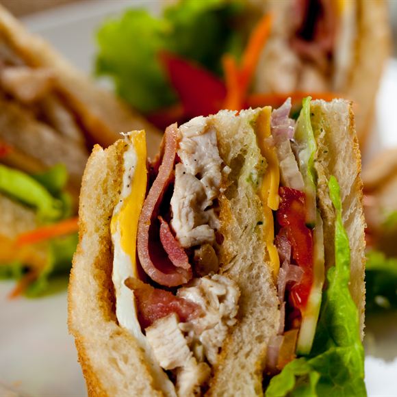 A club sandwich cut through, salad leaves and tomato between the layers.