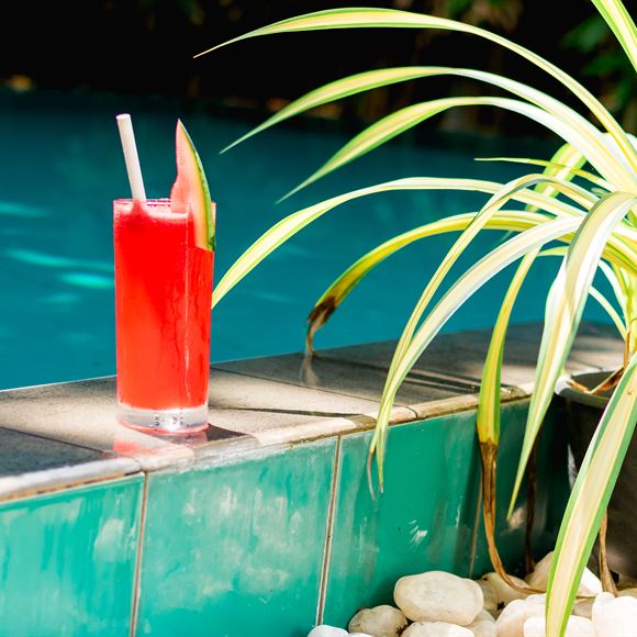 A tall glass of watermelon juice on the edge of the pool at Amber Poolside.