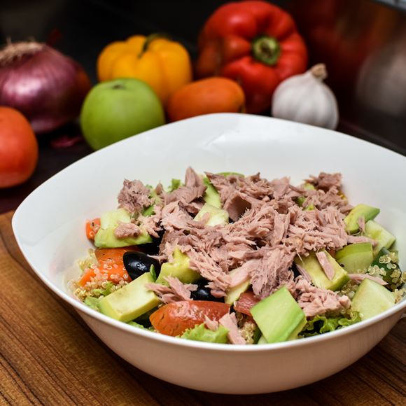A quinoa salad with avocado and tuna in a white bowl.