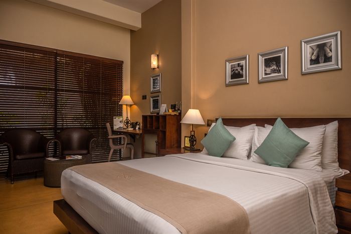 A made bed in a room at Colombo Court with framed photographs above the headboard.