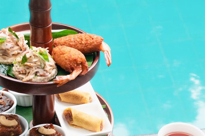 A Ceylon high tea stand beside the pool, savouries on three tiers with cups of tea alongside.