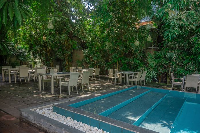 The planted garden at Colombo Court, tables under greenery beside the pool.