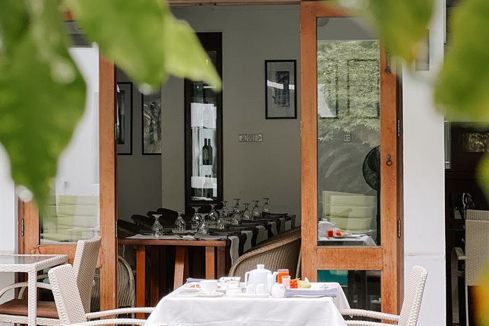 Tables set for breakfast beside the pool at Colombo Court, greenery all around.