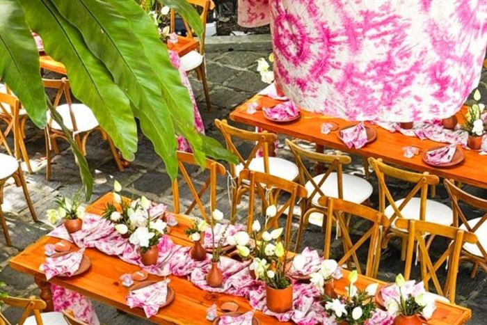 Long tables set for a celebration at Amber Poolside, pink linen and flowers under the trees.