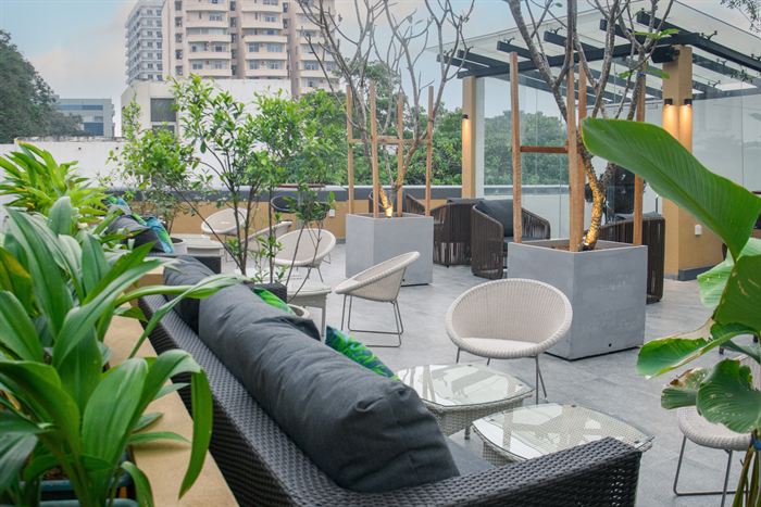 Rooftop seating at Cloud Caf&eacute; & Bar under its glass roof, planted beds between the tables.