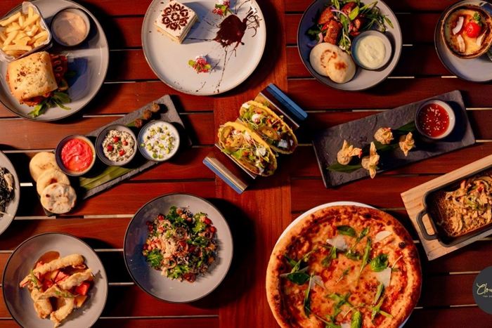 Sharing platters laid across a timber table at Cloud Caf&eacute; & Bar, pizza, dips, skewers and small plates.
