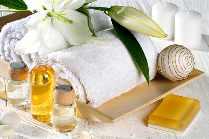 Rolled towels, a lily, candles and small bottles of oil on a spa tray at The Court Spa.