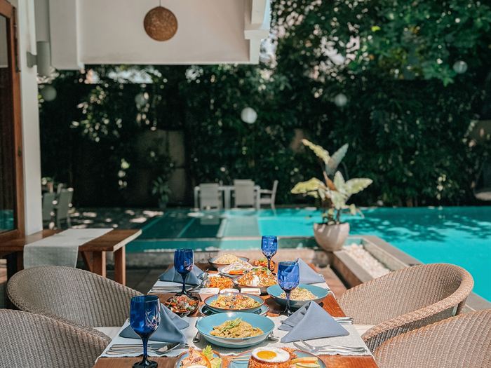 Lunch laid out on a table beside the pool at Amber Poolside, blue glassware on white linen.
