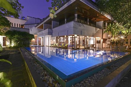 The pool at Colombo Court lit blue after dark, the hotel glowing behind it.