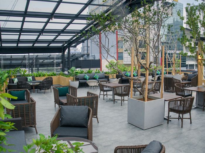 The Cloud Caf&eacute; & Bar rooftop under its glass roof, planted beds between the tables and the Colombo skyline beyond.