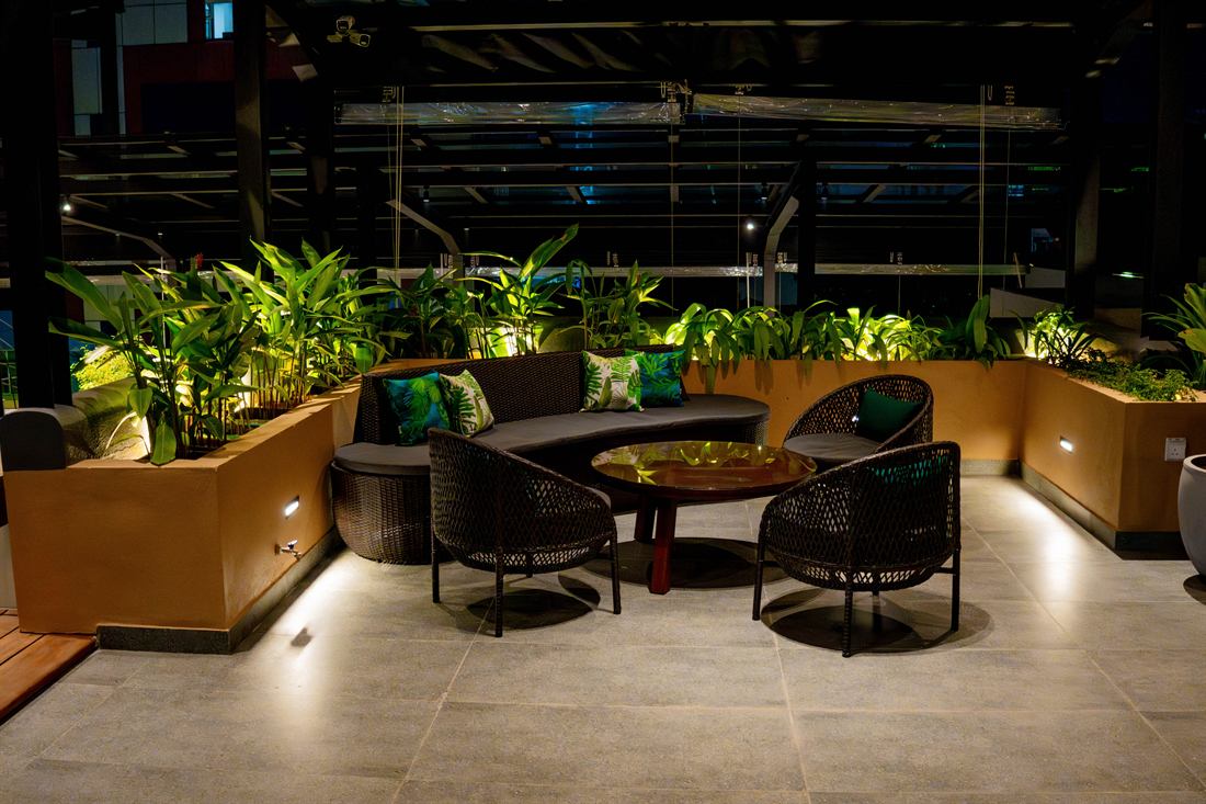 Low seating on the roof at night, warm light over the planting.
