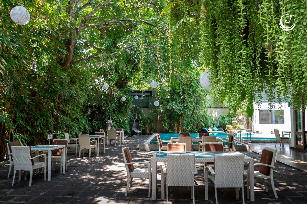 The poolside garden laid with long tables under the trees beside the pool.