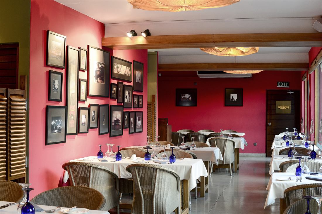 The Scarlet Room laid for private dining, framed photographs along the red wall.