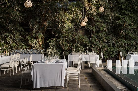 A long table laid in white beside the pool at Colombo Court, bulbs strung through the trees above it.