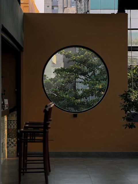 A round window cut into an ochre wall at Colombo Court, framing planting outside.