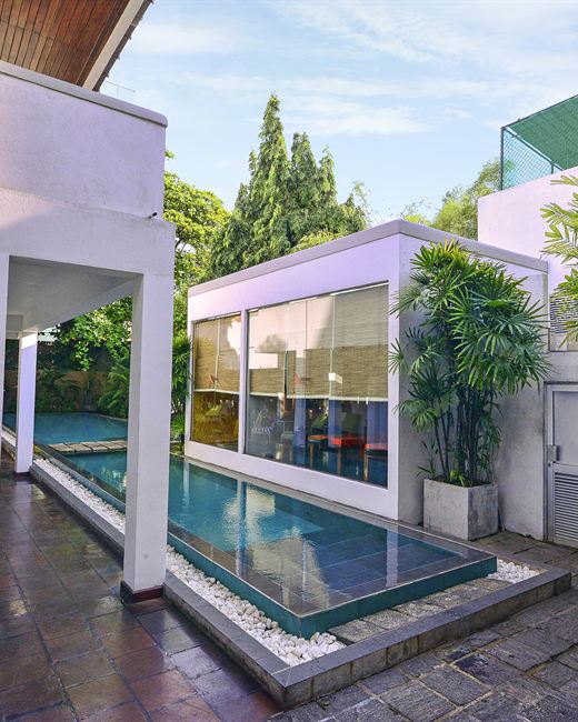 The pool at Colombo Court running between white walls and planting, the water clear and still.