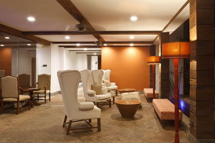 The lobby at Colombo Court, winged armchairs under timber beams and a tall lamp beside the wall.