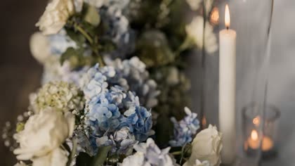 A detail of a wedding table, white florals and candles in tall glass holders.
