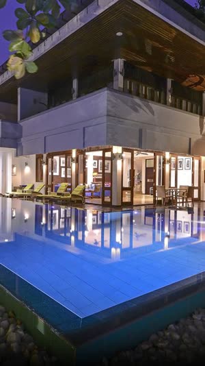 The poolside garden at dusk, the pool lit blue and the hotel glowing around it.