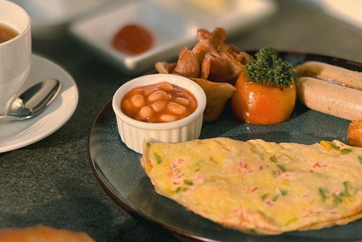 Breakfast at Amber Poolside, an omelette and coffee on a tray beside the water.