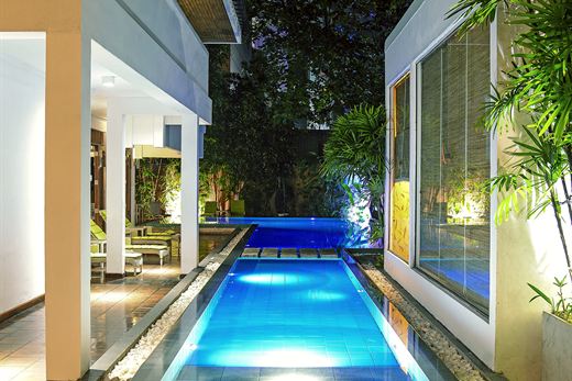 The pool at Colombo Court lit blue after dark, the hotel glowing around it.