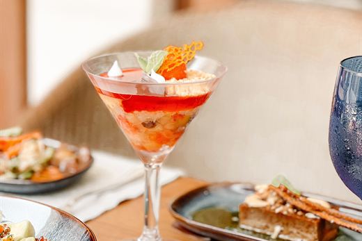 A cocktail in a coupe glass beside small plates.