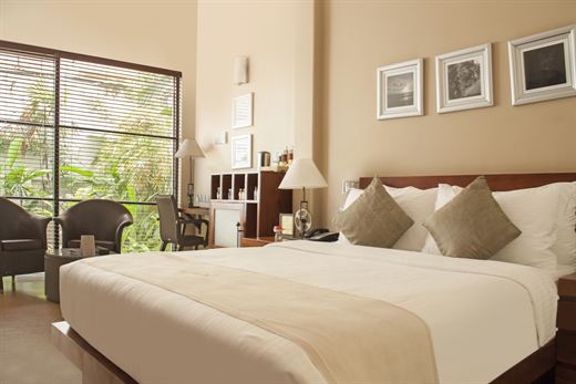 A Deluxe Room at Colombo Court with a queen bed and a tall window onto the garden.