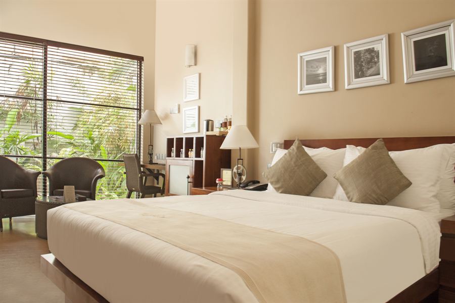 A Deluxe Room, queen bed and a tall window onto the garden.