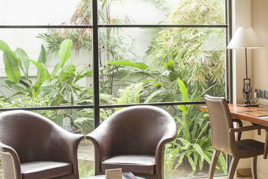 Two chairs and a table outside a Deluxe Room, greenery all around.