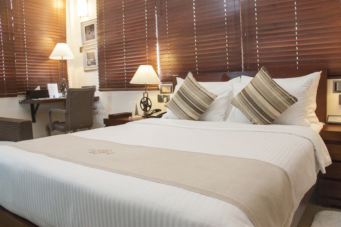 A Deluxe Room with timber blinds and reading lamps either side of the bed.