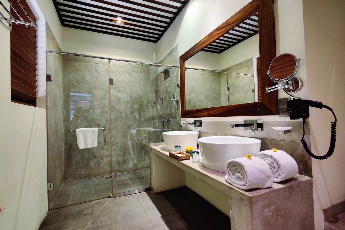 The bathroom in a Deluxe Room, twin basins and a walk-in shower.