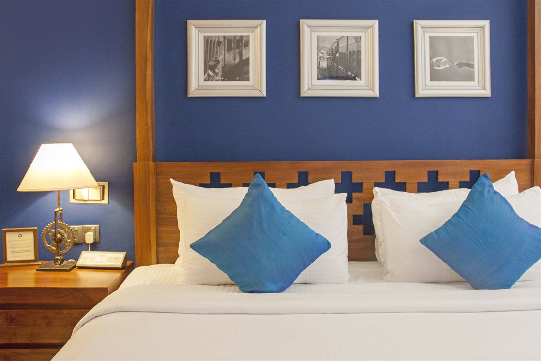 The Luxury Honeymoon Suite bed against the blue wall, framed photographs above it.