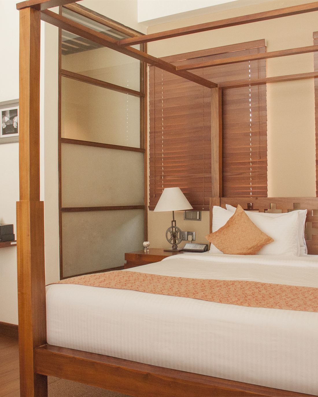 A Luxury Junior Suite with a timber four-poster bed and slatted screens.