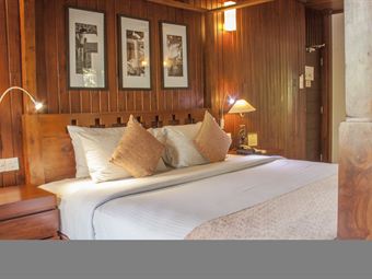 The bed in a Luxury Junior Suite at Colombo Court, timber panelling and reading lamps either side.
