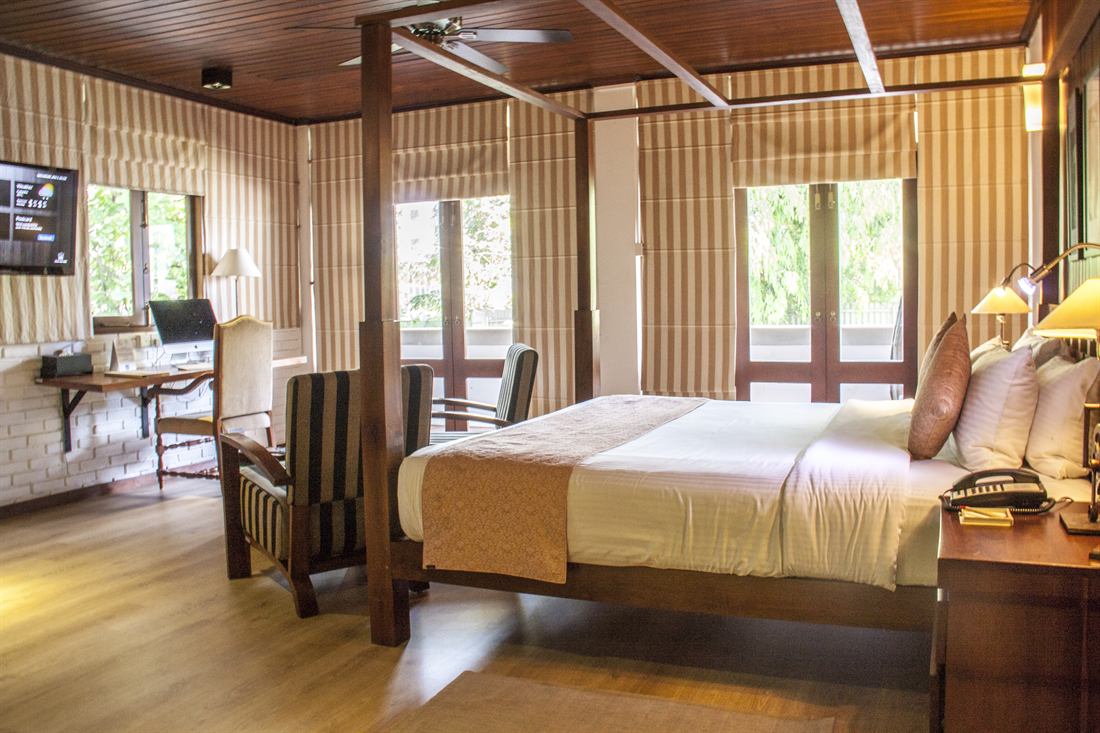 A Luxury Junior Suite seen wide, the bed, seating and the window into the trees.