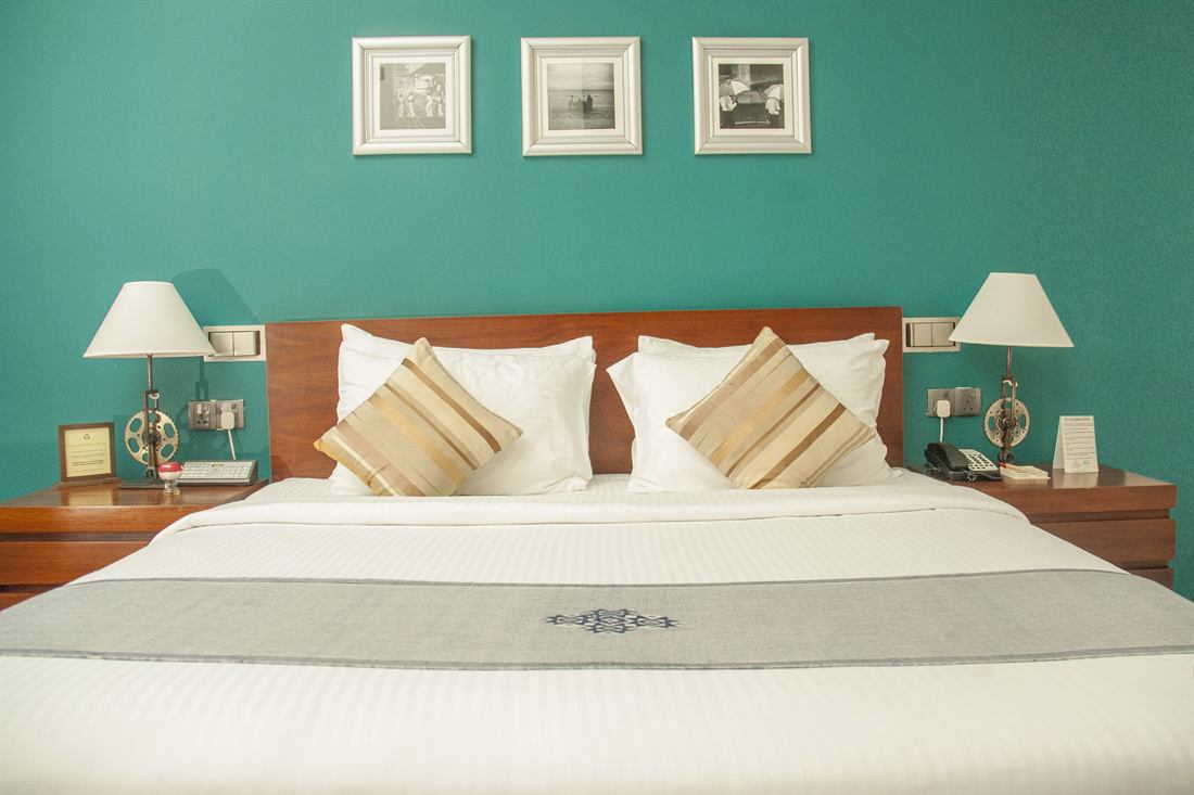 A Superior Deluxe room with a teal wall and framed prints above the bed.