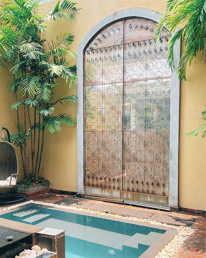 The plunge pool at The Court Spa under a carved arch, palms leaning in from both sides.