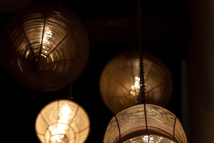 Lampshades made from old bicycle parts hanging in the dark at Colombo Court, filament bulbs glowing inside them.