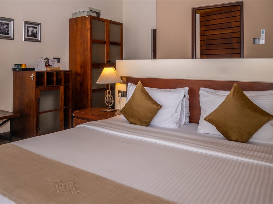 A Superior Deluxe room at Colombo Court with a king bed, timber cabinetry and slatted blinds.