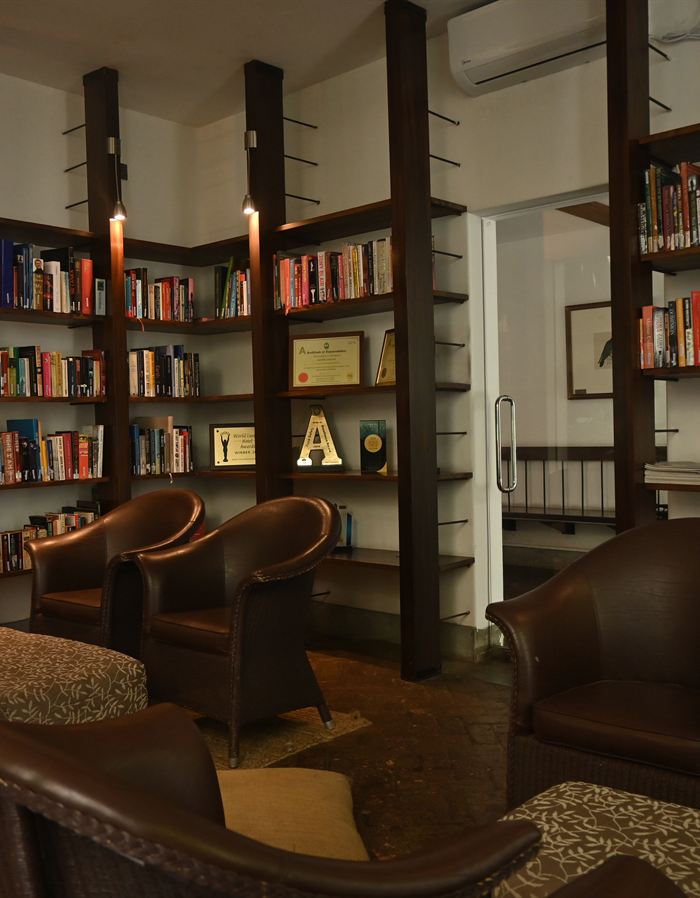 The library at Colombo Court, full shelves either side of leather armchairs under a timber ceiling.
