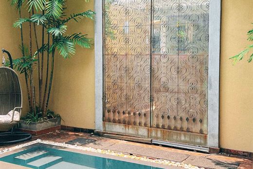 The plunge pool at The Court Spa beneath a carved metal screen, palms on both sides.