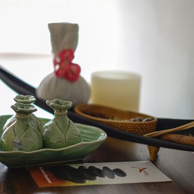 Herbal compresses and a lit candle laid out before a treatment.