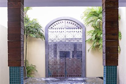 The jacuzzi at The Court Spa set between timber columns beneath a carved screen, palms on both sides.