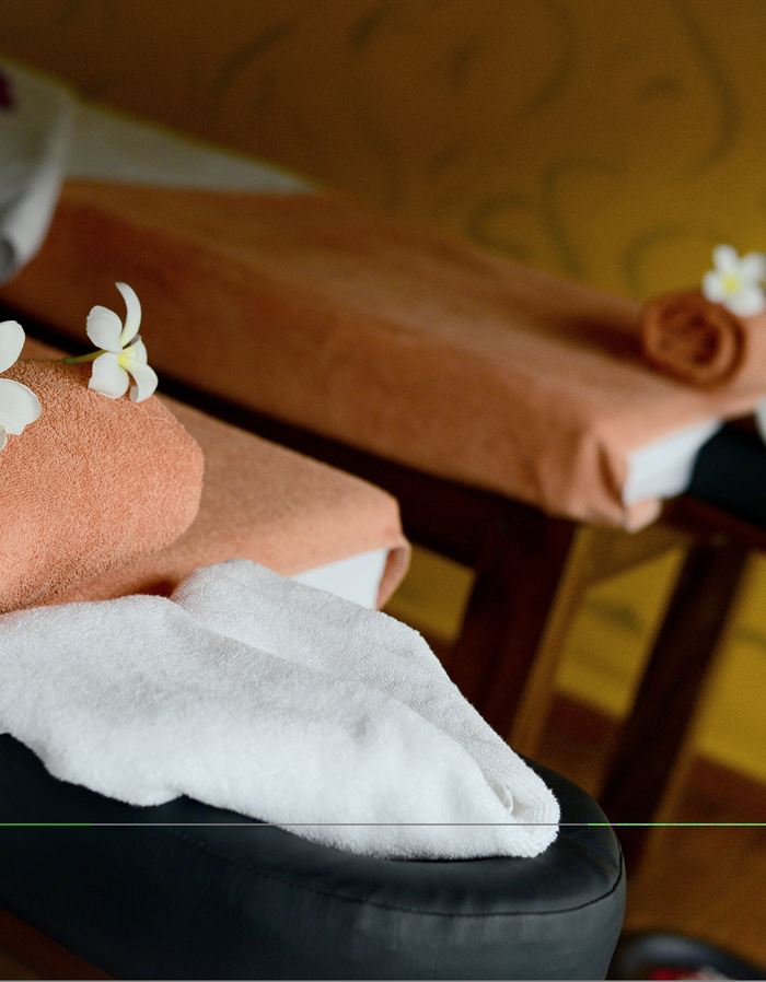 Rolled towels and frangipani laid out on a treatment bed at The Court Spa.