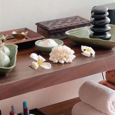 Massage oils, hot stones and frangipani laid out on a timber table at The Court Spa.