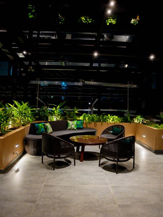 Tables on the rooftop at Cloud Caf&eacute; & Bar at night, lit from below among planters.